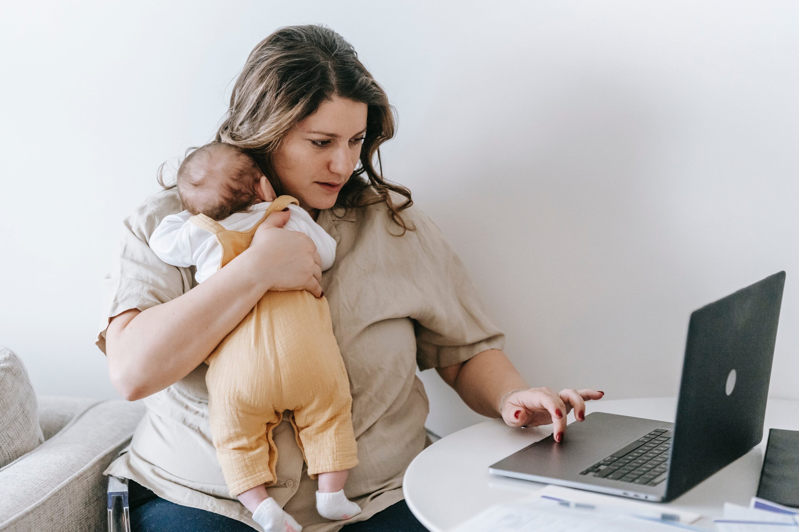 赤ちゃんを抱く女性がパソコンを操作している写真